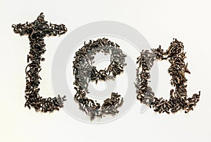 The inscription tea` lined in tea leaves of black leaf tea on a white background