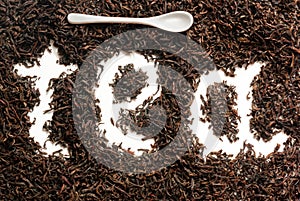 The inscription tea` lined in tea leaves of black leaf tea on a white background