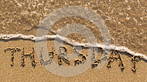 Inscription THURSDAY on a gentle beach sand with the soft wave