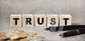 Inscription TRUST on wooden cubes on a gray background