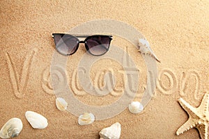The inscription Vocation and beach accessories on the sandy beach. Summertime