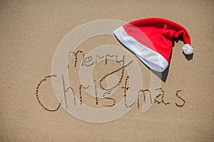 Inscription on the wet sand and cap of Santa Claus