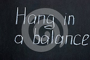 The inscription in white chalk on a dark board Hang in a balance photo