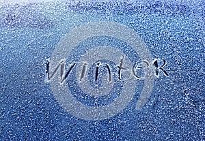 Inscription the word winter scraped on the frosty glass covered with white crystals and painted on the car window on a winter cold