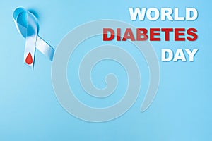 Inscription world diabetes day and blue ribbon awareness with red blood drop on a blue background