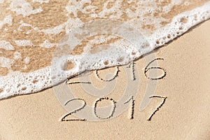 2016 2017 inscription written in the wet yellow beach sand being