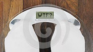 Inscription WTF on bathroom scales digital display