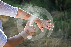 Insect repellent. Woman spraying mosquito repellent on hand.