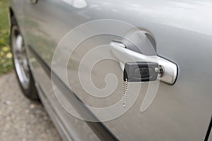 Inserted key in the car door outdoors. Close up of a carbody with the key left in the lock. Unlocking the vehicle doors