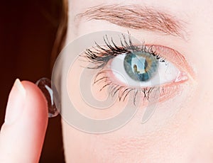 Inserting a contact lens in female eye
