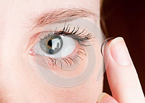 inserting a contact lens in female eye