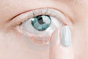 Inserting a contact lens in female eye
