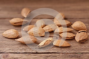 Inshell almonds and peeled kernels are on wooden table