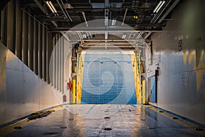 Inside auto deck on the Greek ferry. Lifted bow ramp and the cloudy sky on the background