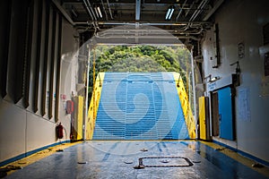 Inside auto deck on the Greek ferry. Opening bow ramp and the cloudy sky on the background