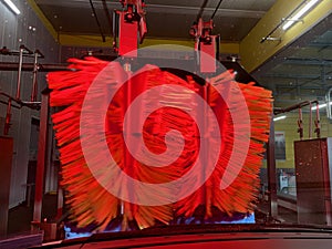 Inside automatic conveyorized tunnel car wash. View from inside car, red rotating drying brushes.