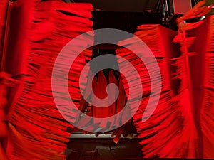 Inside automatic conveyorized tunnel car wash. View from inside car, red rotating drying brushes.