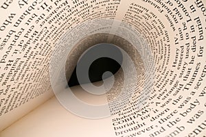 Inside the book concept. Latin letters and words on an tunnel shaped, perspective book page with black dramatic light. Education,