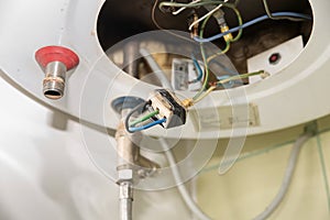 Inside of the broken water heater or boiler with electric wires and pipes for installation of the hoses with rust and burn selecti