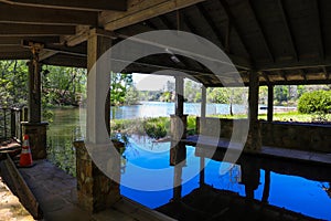 Inside a brown wooden boat house with vast blue lake water surrounded by lush green trees and plants at Callaway Gardens