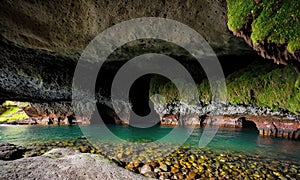 the inside of a cave with water and moss growing on the rocks