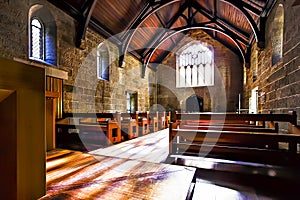 Inside of a church with wooden benches and floor