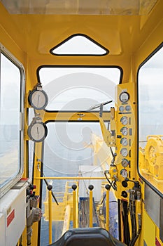 Inside of crane cabin at oil and gas wellhead platform there are pressure gauge and joy stick for control movement.