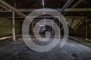 Inside dark abandoned ruined wooden decaying hangar with rotting columns