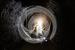 Inside dark round underground sewer tunnel