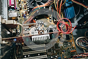 Inside details of the old personal computer. Cooler, motherboard, wires and video card in the dust. Broken PC