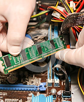 Inside details of the old personal computer. Cooler, motherboard, wires and video card in the dust. Man is holding cables in his