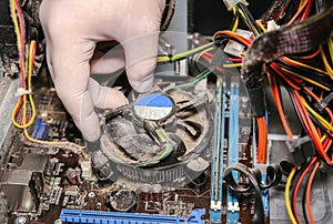Inside details of the old personal computer. Cooler, motherboard, wires and video card in the dust. Man is holding cables in his