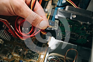 Inside details of the old personal computer. Cooler, motherboard, wires and video card in the dust. Man is holding hard disk drive