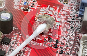 Inside details of the old personal computer. Dirty Motherboard and video card in the dust. Man is cleaning wires with a brush.