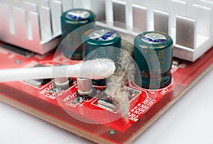 Inside details of the old personal computer. Dirty Motherboard and video card in the dust. Man is cleaning wires with a brush.