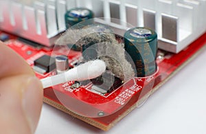 Inside details of the old personal computer. Dirty Motherboard and video card in the dust. Man is cleaning wires with a brush.