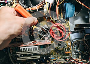 Inside details of the old personal computer. Motherboard, cable wires and video card in the dust. Man is repairing broken PC with