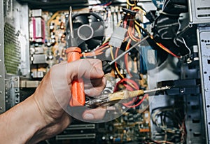 Inside details of the old personal computer. Motherboard, cable wires and video card in the dust. Man is repairing broken PC with