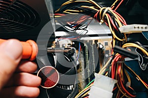 Inside details of the old personal computer. Motherboard, cable wires and video card in the dust. Man is repairing broken PC with