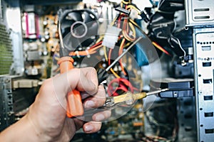 Inside details of the old personal computer. Motherboard, cable wires and video card in the dust. Man is repairing broken PC with