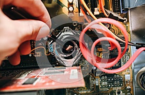 Inside details of the old personal computer. Motherboard and video card in the dust. Man is cleaning wires with a brush. Broken PC