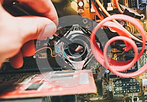 Inside details of the old personal computer. Motherboard and video card in the dust. Man is cleaning wires with a brush. Broken PC