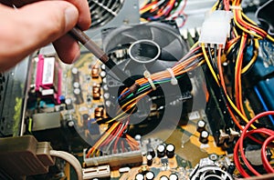 Inside details of the old personal computer. Motherboard and video card in the dust. Man is cleaning wires with a brush. Broken PC