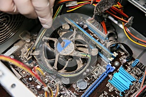 Inside details of the old personal computer. Motherboard and video card in the dust. Man is cleaning wires with a brush. Broken PC