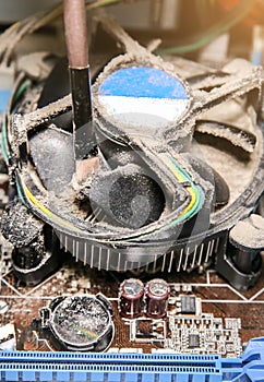 Inside details of the old personal computer. Motherboard and video card in the dust. Man is cleaning wires with a brush. Broken PC