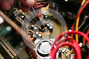 Inside details of the old personal computer. Wires and video card in the dust. Man is cleaning motherboard with a brush. Broken PC