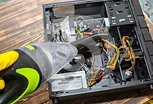 Inside details of the personal computer. Man is cleaning wires with vacuum cleaner. Small hoover. Motherboard and video card in