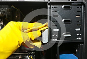 Inside details of the personal computer. Man is cleaning wires in yellow gloves. Motherboard and video card in the dust. Broken PC