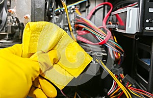 Inside details of the personal computer. Man is cleaning wires in yellow gloves. Motherboard and video card in the dust. Broken PC