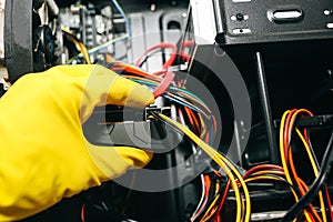 Inside details of the personal computer. Man is cleaning wires in yellow gloves. Motherboard and video card in the dust. Broken PC